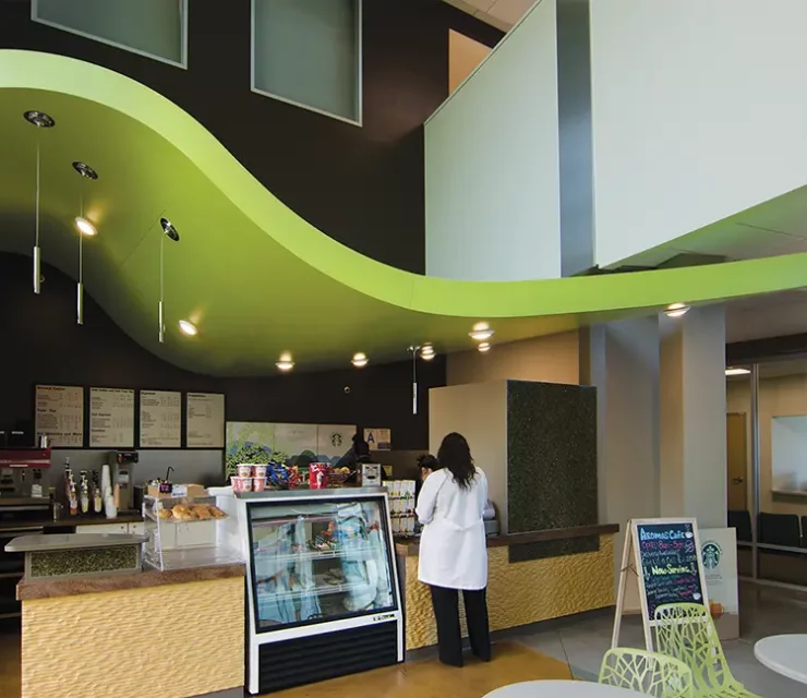 Hospital cafe with bright green undulating ceiling cloud and textured counter front