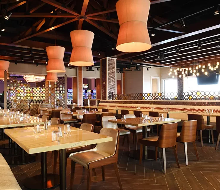 Restaurant dining area with dark wood truss ceiling and large fabric pendant fixtures